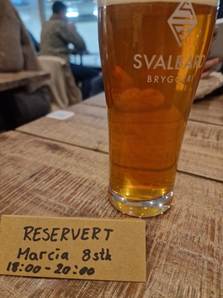 Un bicchiere di birra sopra un tavolo con a fianco un biglietto di "riservato"