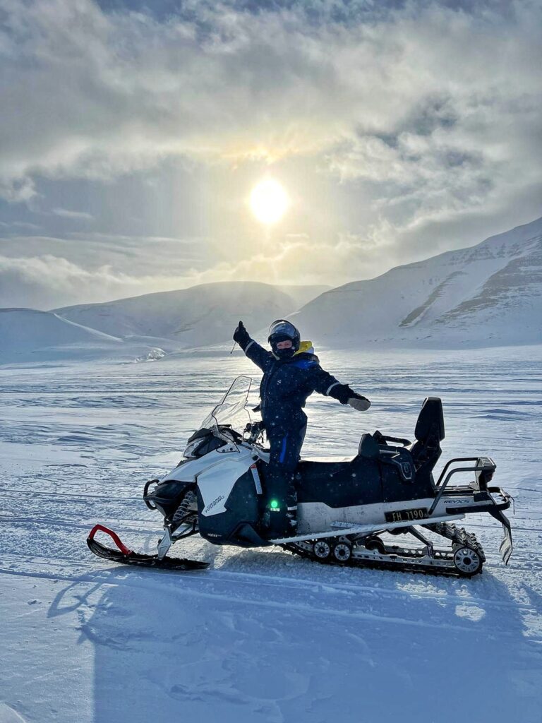 Persona in piedi su una motoslitta ferma in una valle innevata