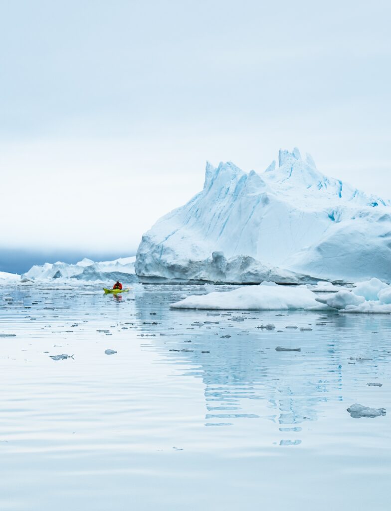 Una persona in kayak di fronte agli icebergs