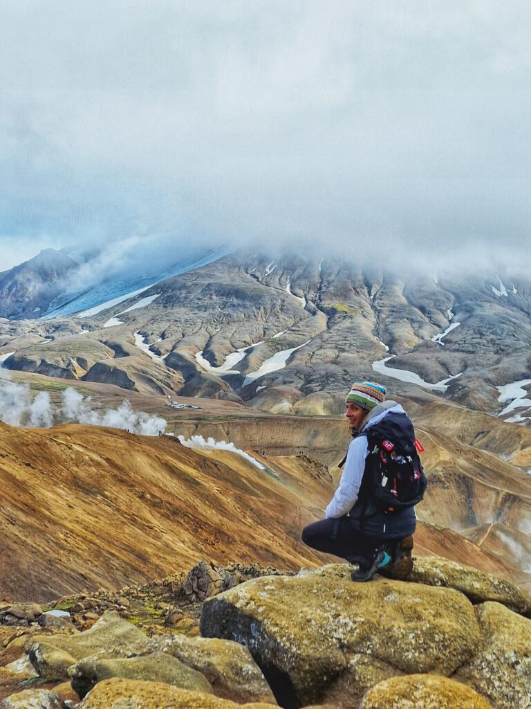 Persona di spalle e sullo sfondo montagna colorata e nuvole basse