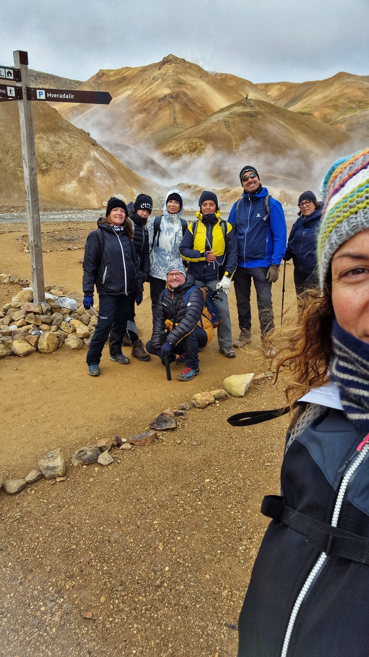 Gruppo di persone fra montagne gialle e geyser