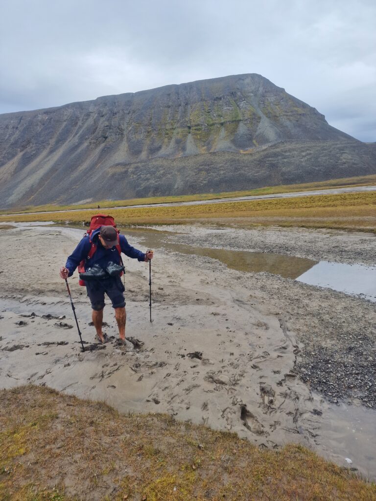 Persona con le gambe nel fango e una montagna dietro