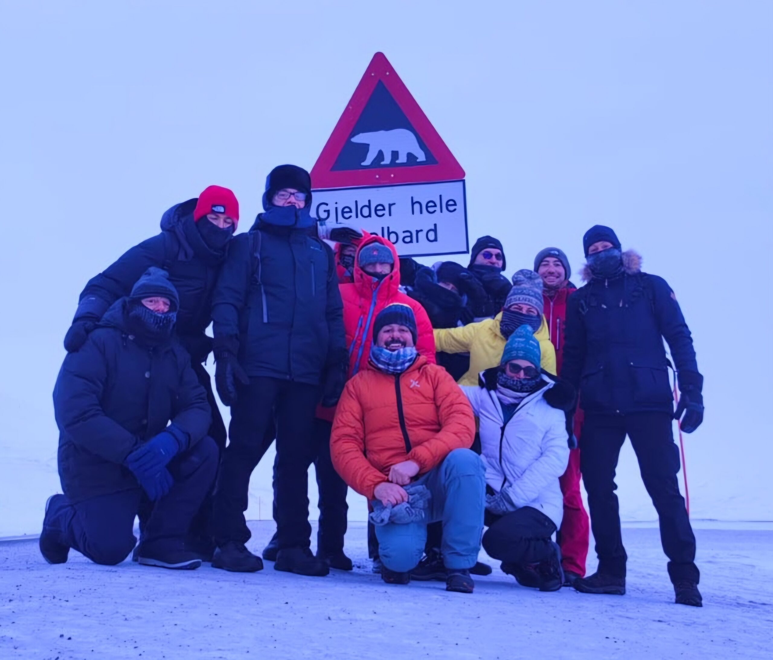 Persone in tuta da sci davanti a cartello pericolo orsi polari